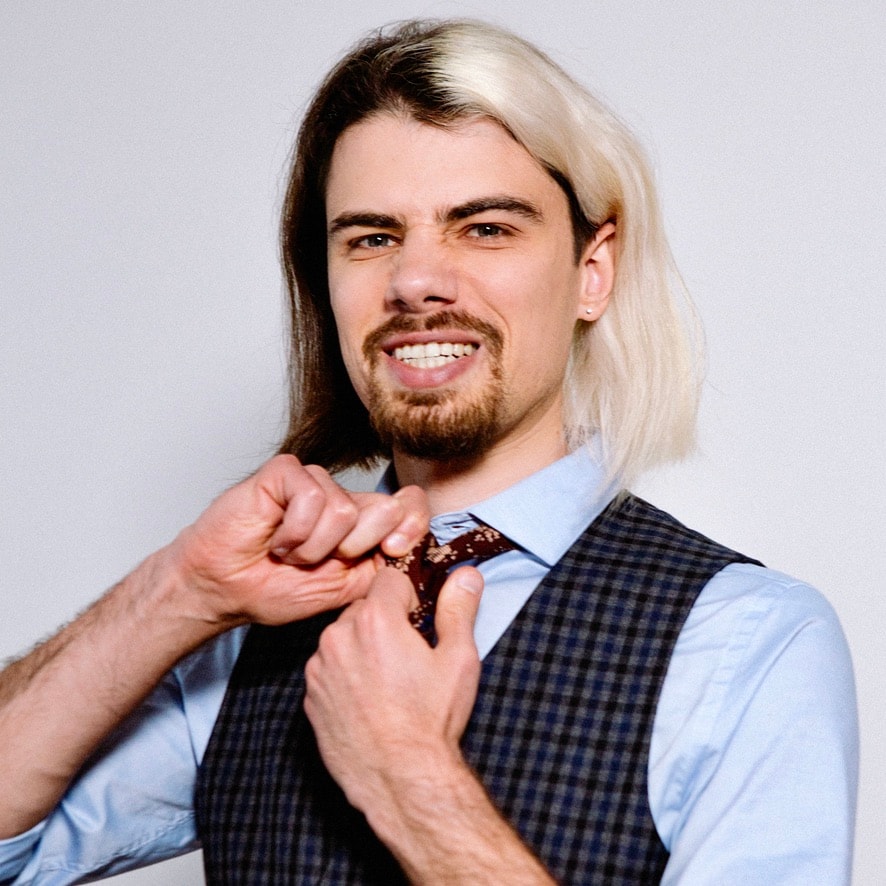 Photo of Alex. Wearing a costume and has slightly log har that is blonde on one side and brown on the other.